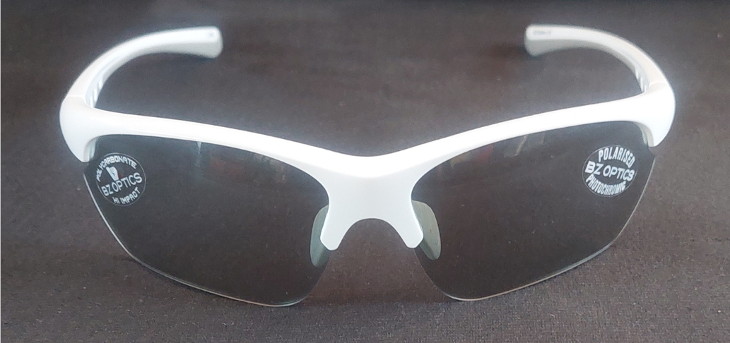 White-framed sunglasses with dark lenses on a reflective surface